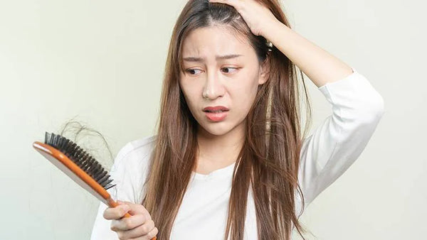 wanita memegang rambut rontok